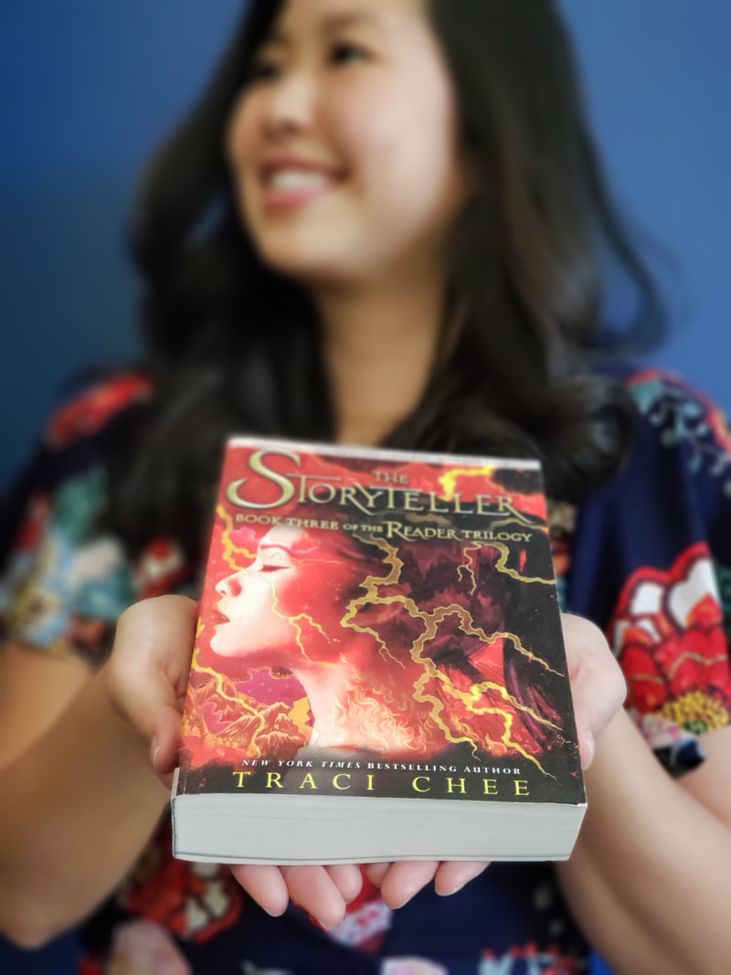 photo of Traci Chee holding an ARC of THE STORYTELLER