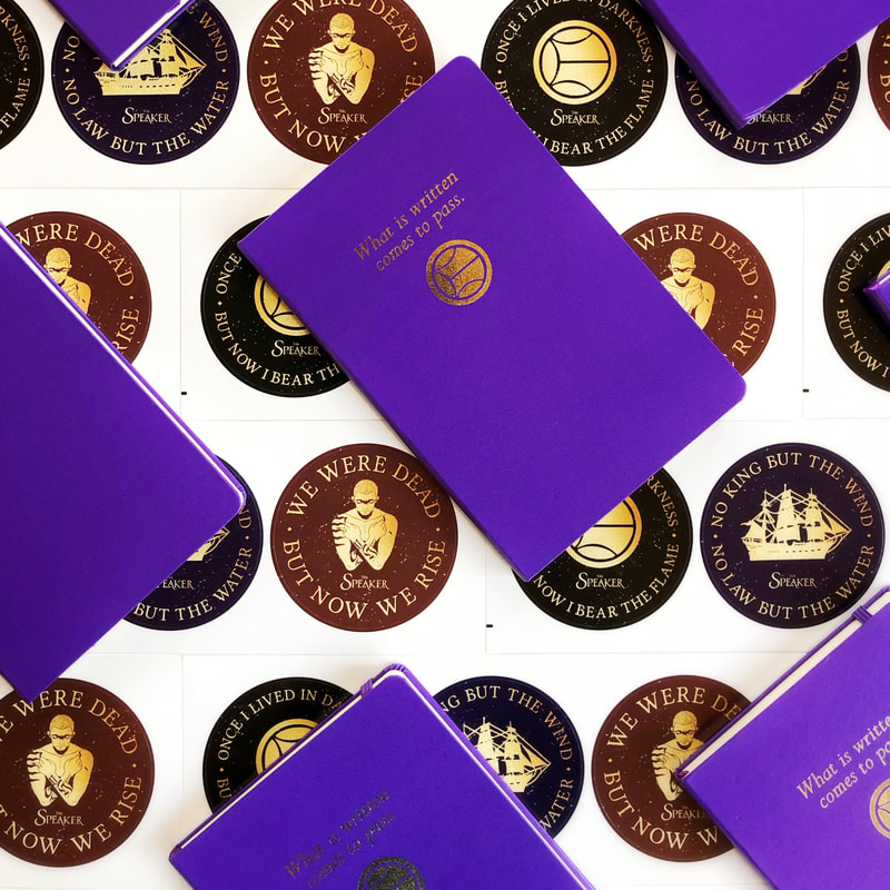 purple notebooks with gold foil lettering on a background of round stickers