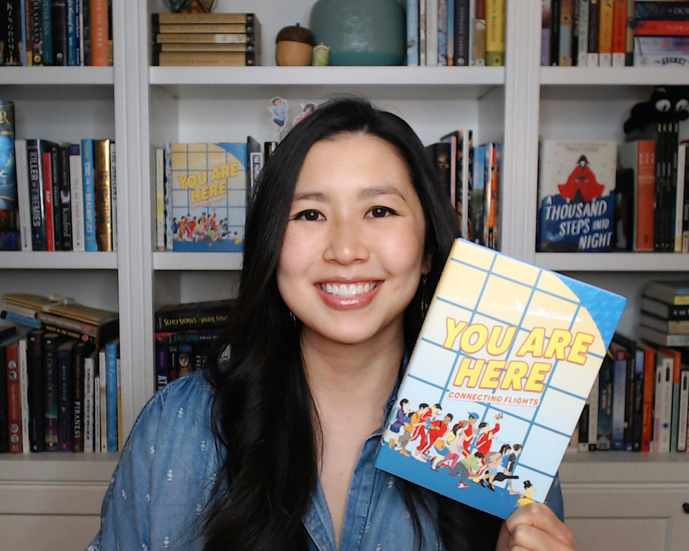 Traci Chee in front of white bookshelves with many books on them, smiling and holding up a copy of YOU ARE HERE: CONNECTING FLIGHTS