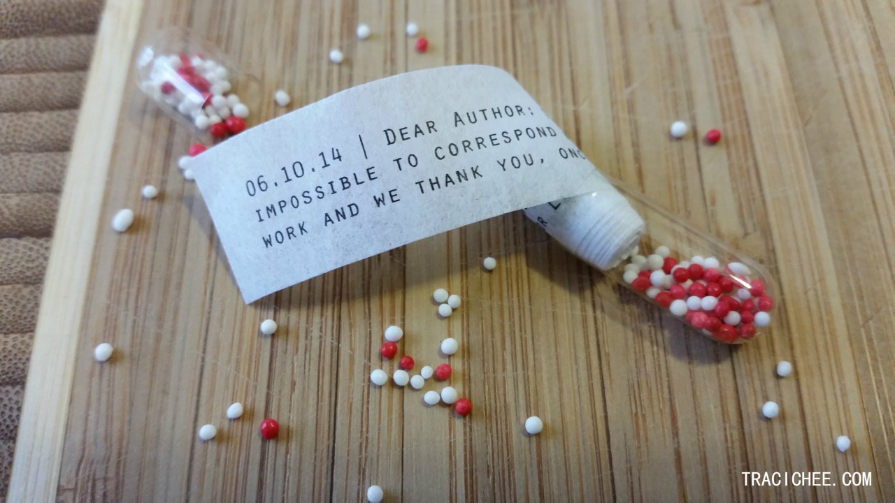 A clear capsule, filled with tiny medicine pellets and rolled up rejection letter.