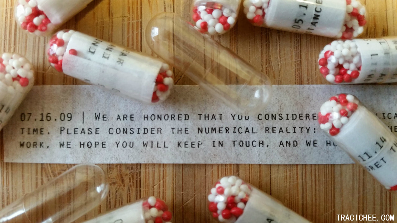 An unrolled rejection letter surrounded by capsules.