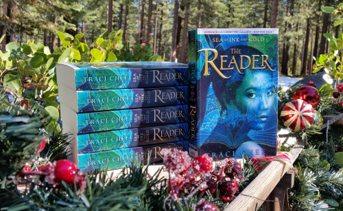 photo of a stack of advanced copies of The Reader on a sled with holly berry garlands in the snow
